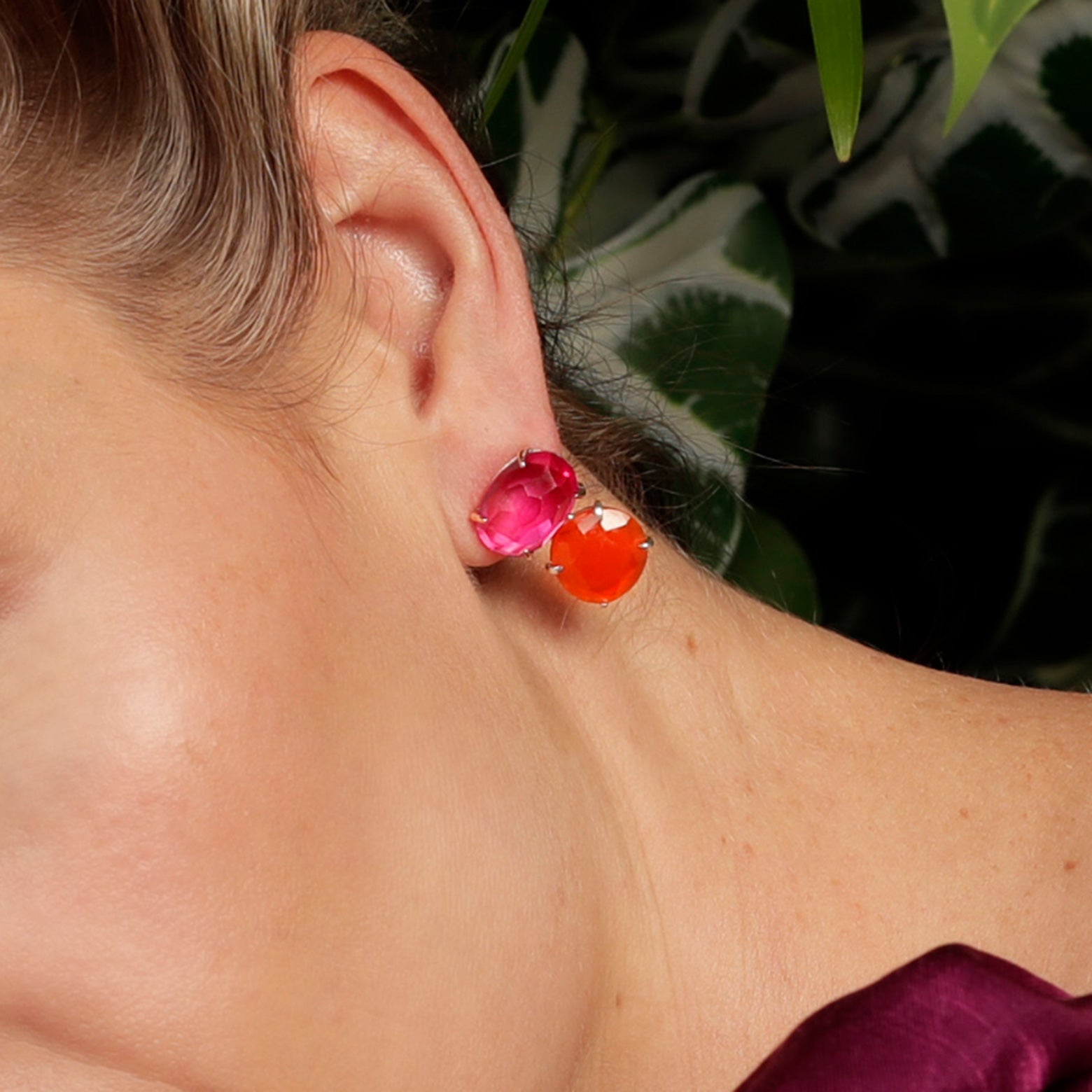 A close up of an ear wearing the Kelly Woodcroft bottle brush earrings earrings with pink and red oval shaped stones set in silver