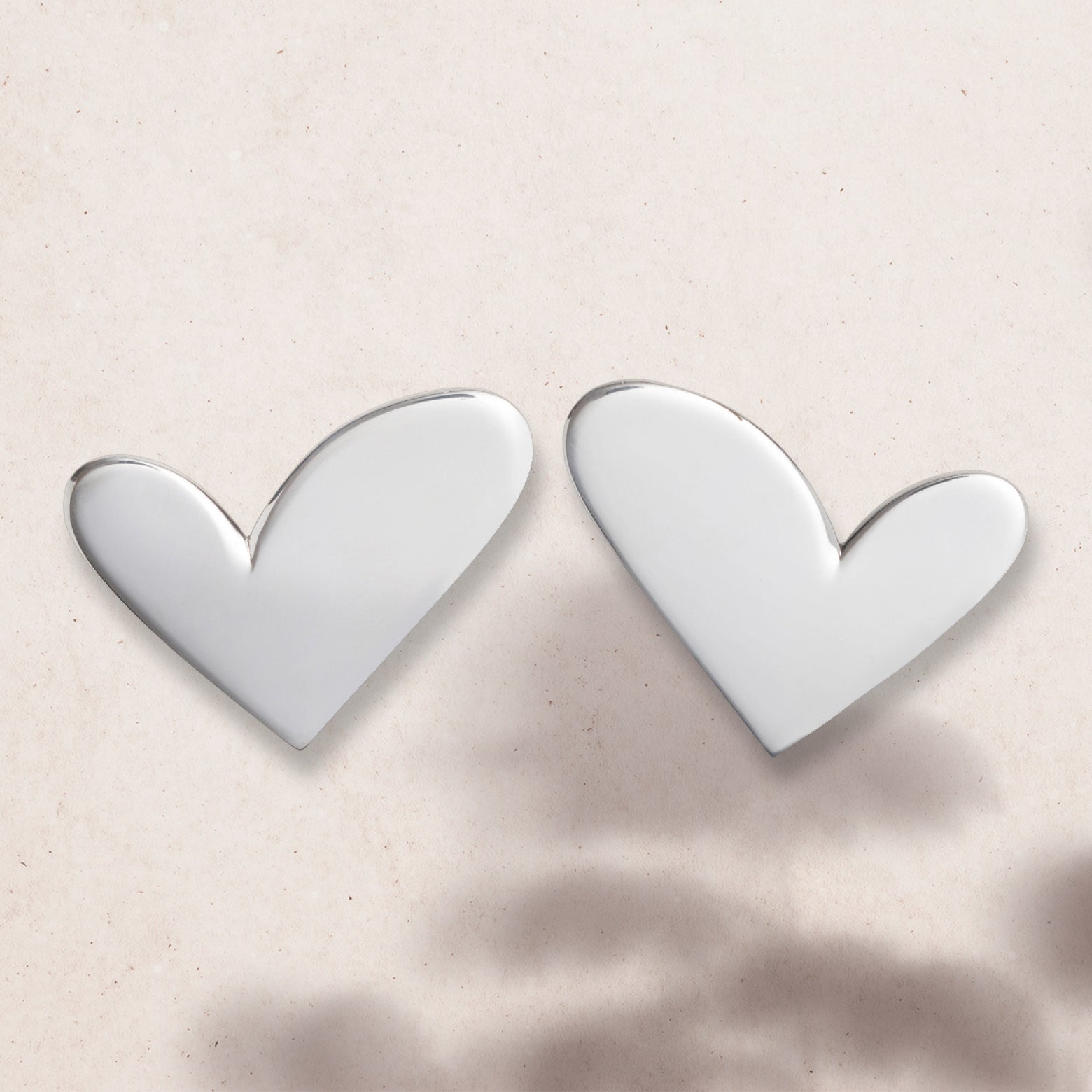 Flat lay of asymmetric silver heart earrings