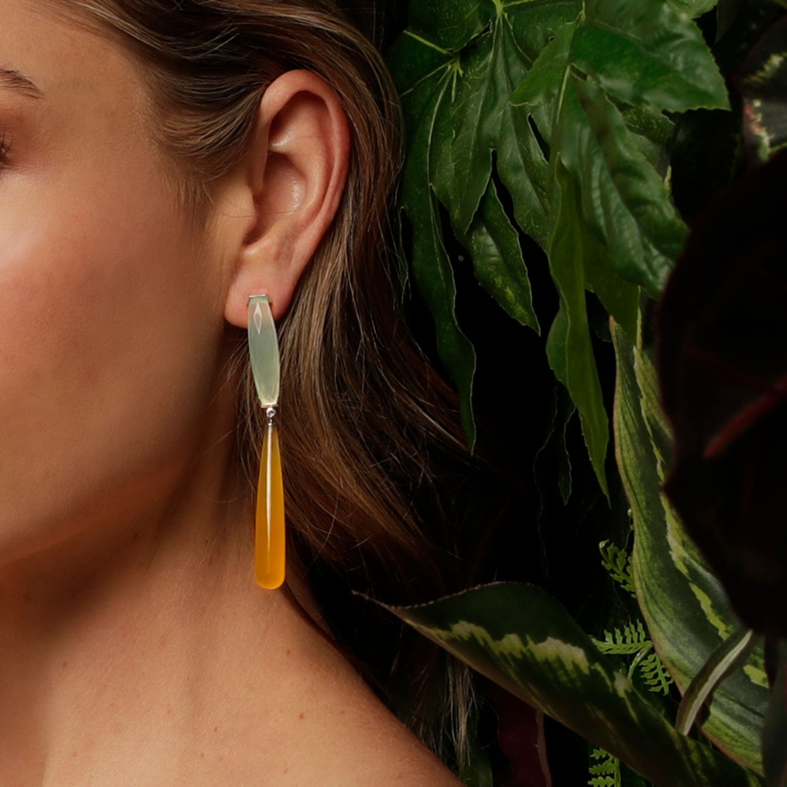 Close up of an ear wearing the Kelly Woodcroft parrot fish stone dangle earrings with light blue and rich yellow stones.